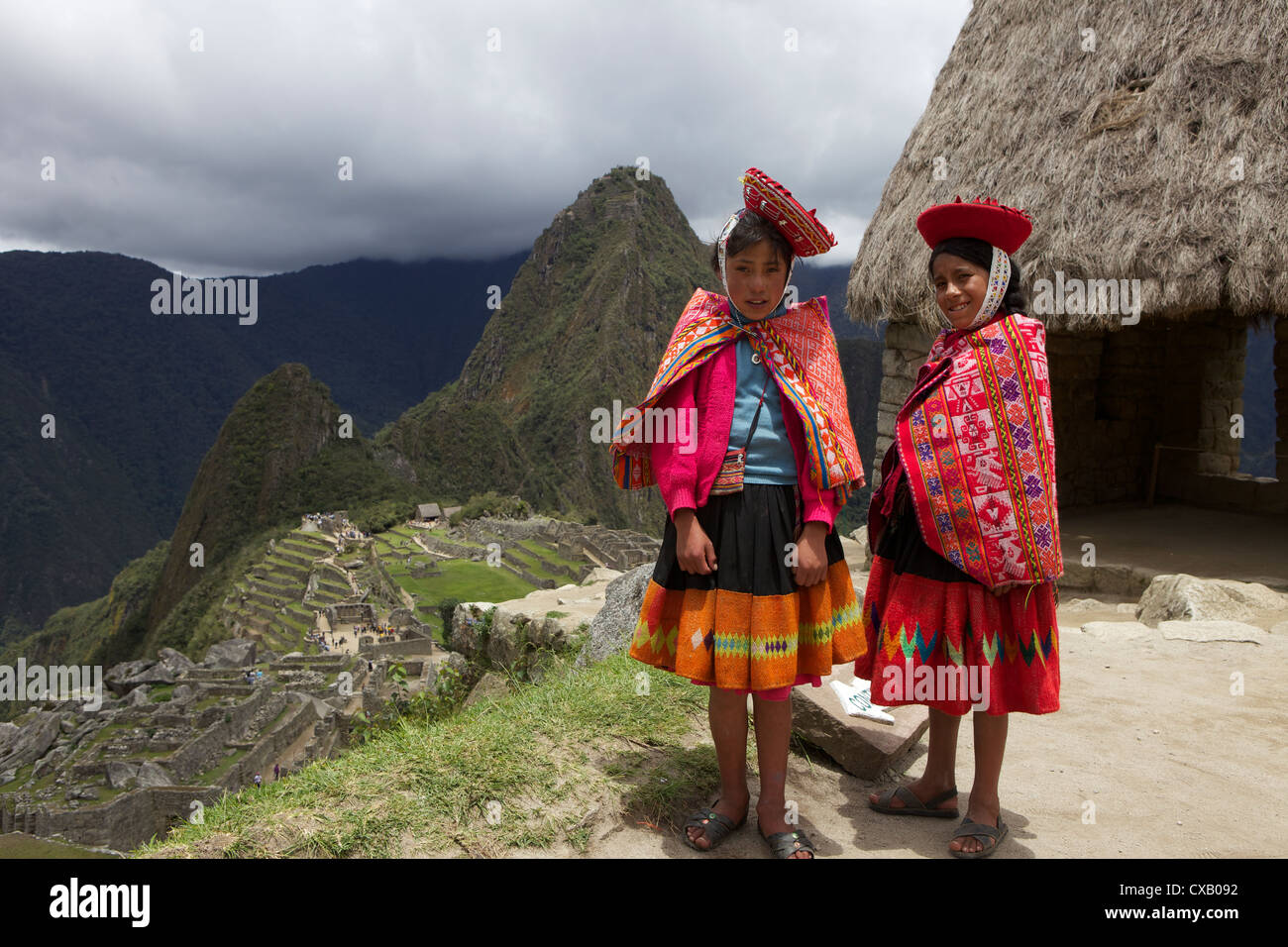 Traditionally dressed children looking over the ruins of Machu Picchu, Vilcabamba Mountains, Peru, South America Stock Photo