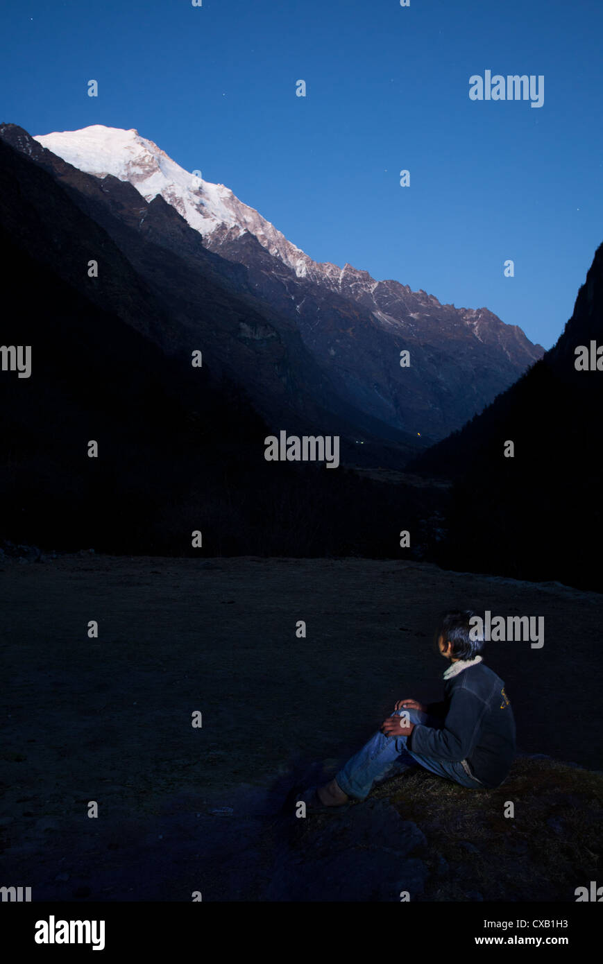 Nepalese man looking up at a snowcapped mountain at night, Langtang Valley, Nepal Stock Photo