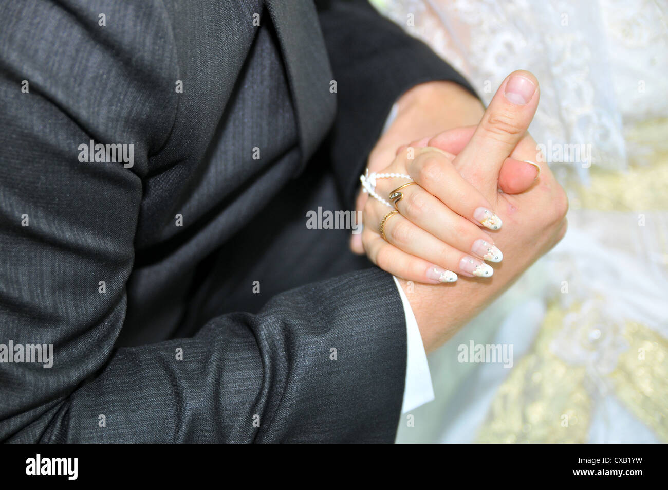 hands of newlyweds with a wedding ring and a bouquet of flowers Stock Photo