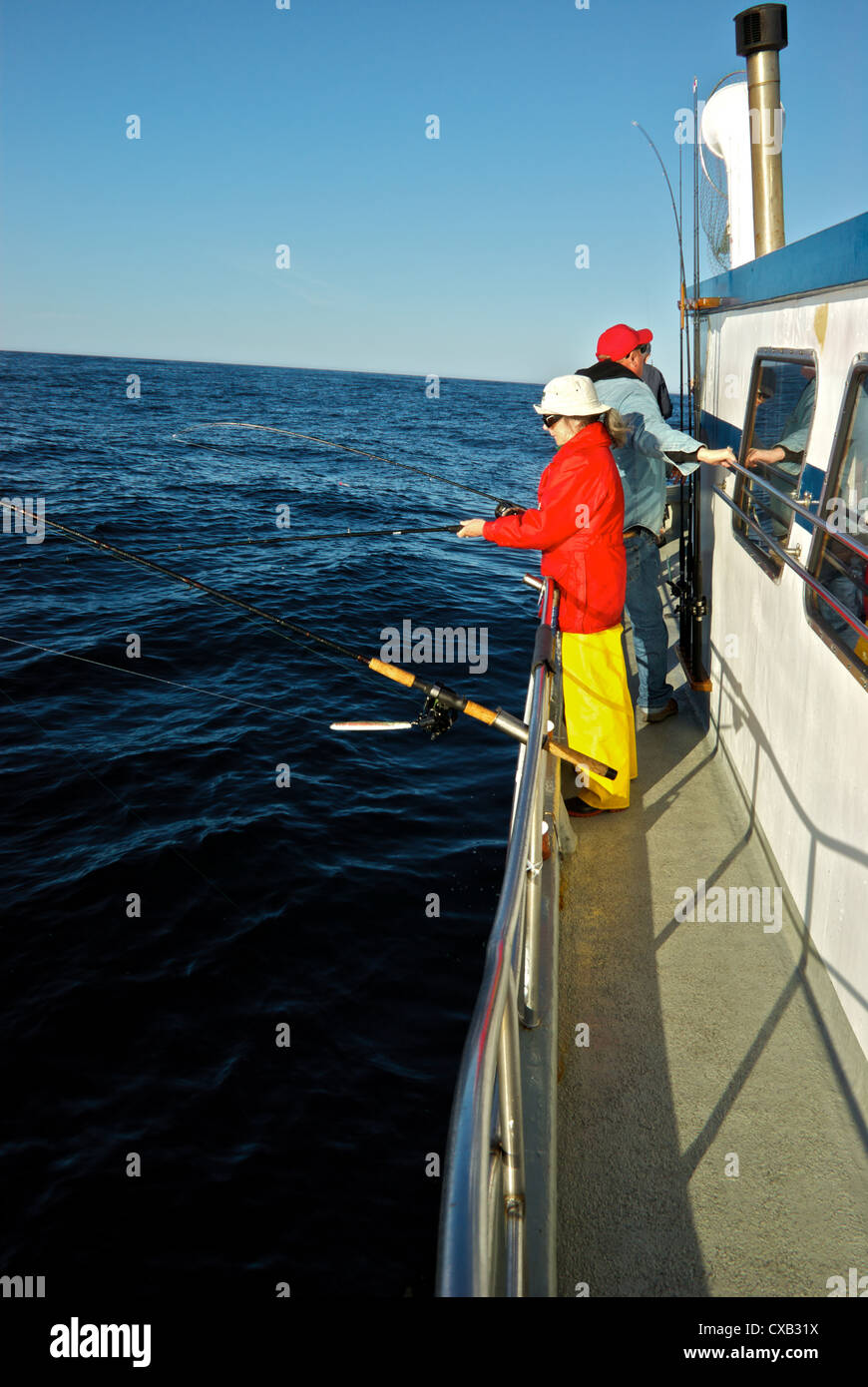 Anglers drift jigging open big rollers Pacific Ocean Ucluelet BC aboard big group charter fishing party boat Stock Photo