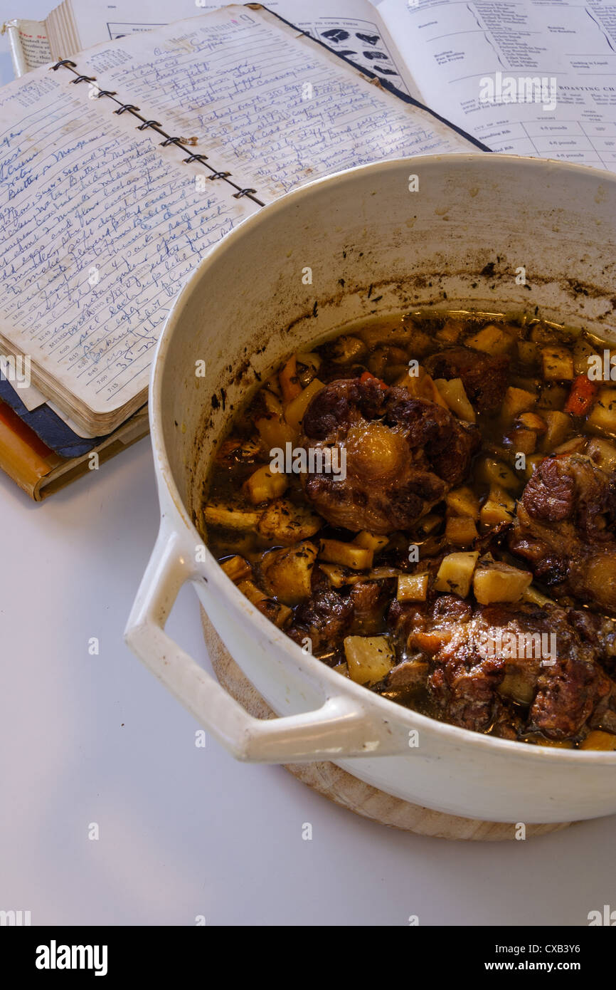 Oxtail stew in white cast iron dutch over with old cookbooks and recipes Stock Photo