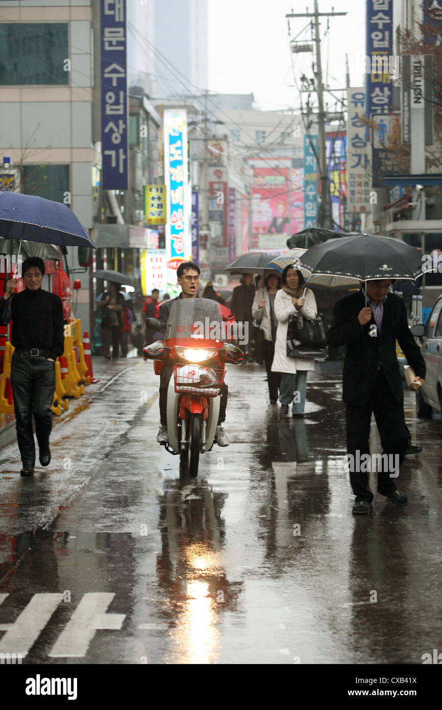 Seoul, pedestrians and motorcyclists on wet road Stock Photo