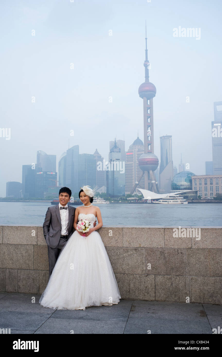 Young married couple posing for wedding photographs on The Bund with skyline of Pudong financial district  rear Shanghai China Stock Photo