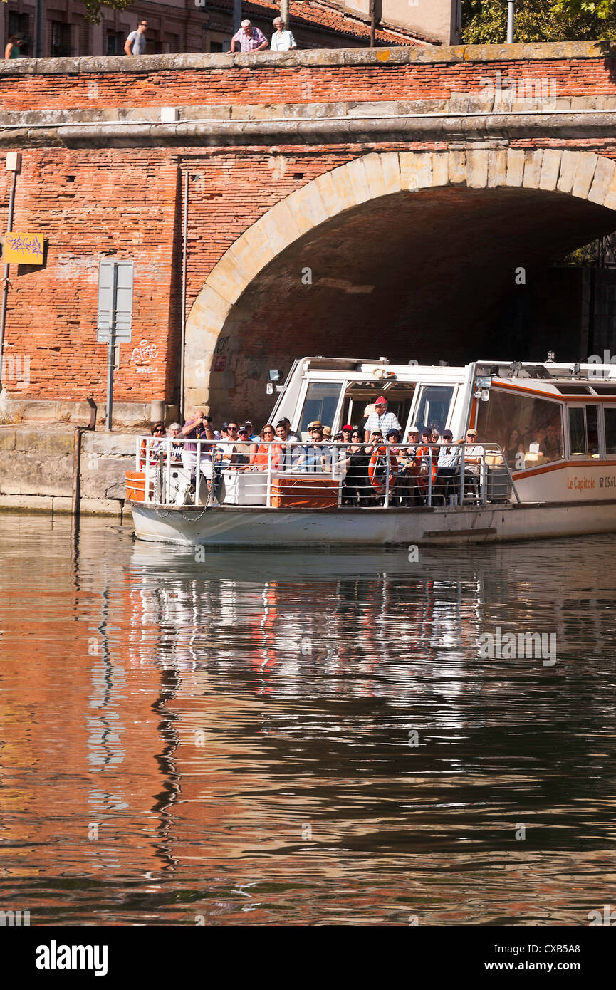 Tourist Boat Exiting the Canal de Brienne into the Garonne River Through a Red Bricked Arch in Toulouse Midi-Pyrenees France Stock Photo