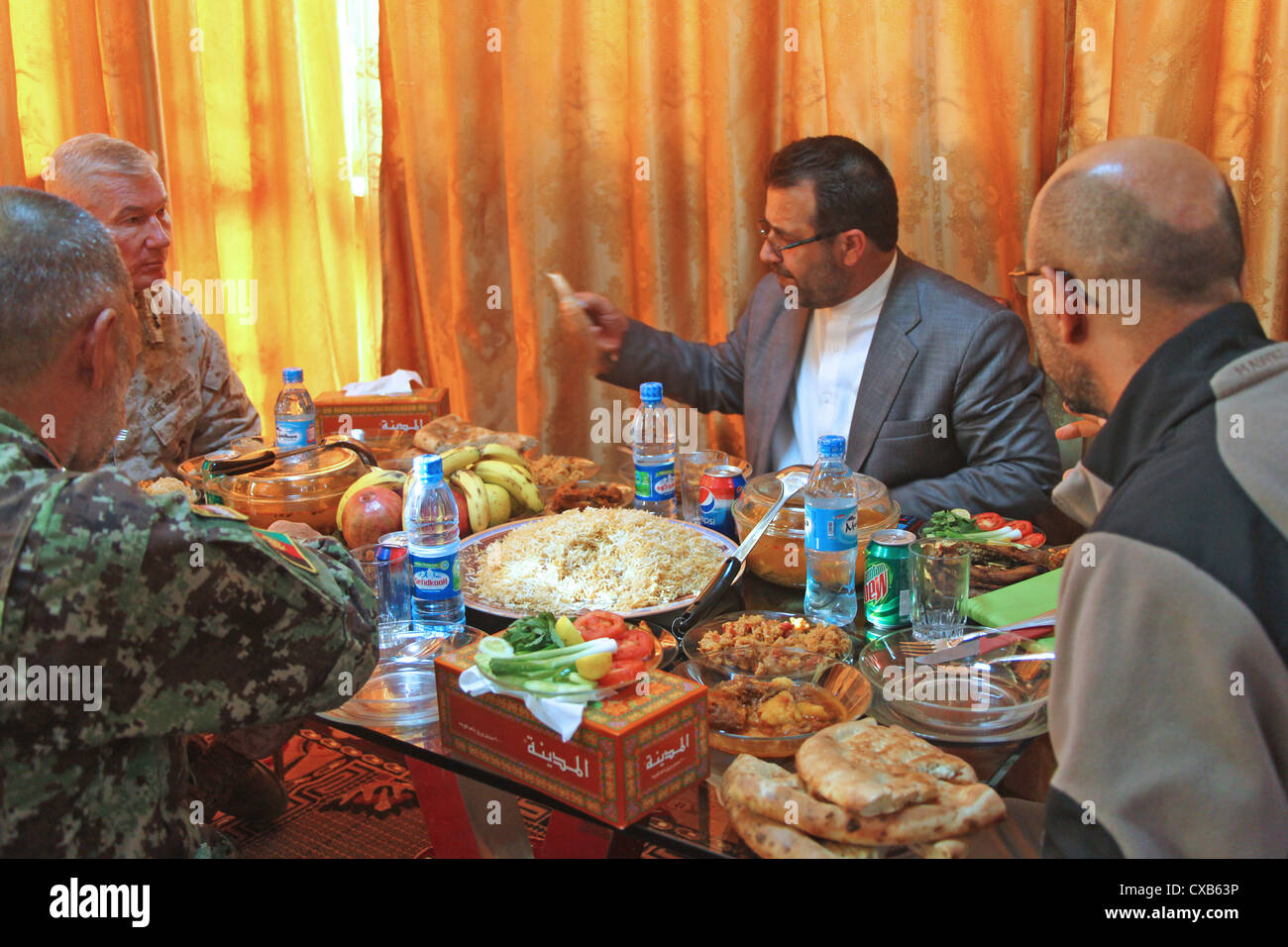Major General John Toolan (far left) talks over lunch with Helmand Provincial Governor Gulab Mangal November 28, 2011 in Lashkar Gah, Afghanistan. The meeting called a Transition Shura, was held to present security plans for transitioning Nawa and Nada districts into Afghan control. Stock Photo