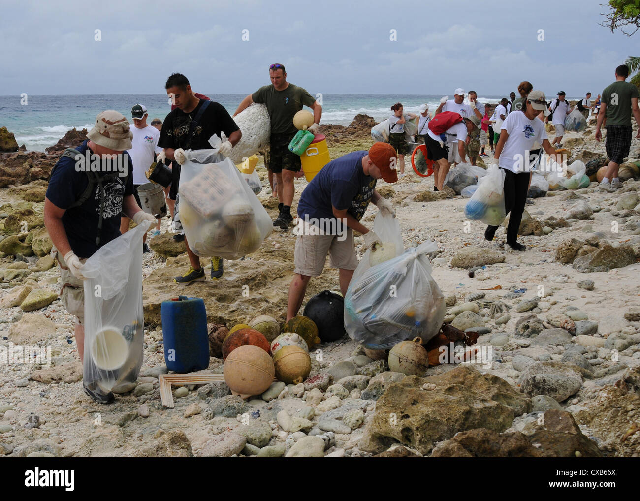 Service members and residents of Diego Garcia, British Indian Ocean Territory, clean up trash at Barton Point September 13, 2012. More than 130 personnel attended the beach cleanup, assisting in the collection of 4,100 lbs. of trash. Stock Photo