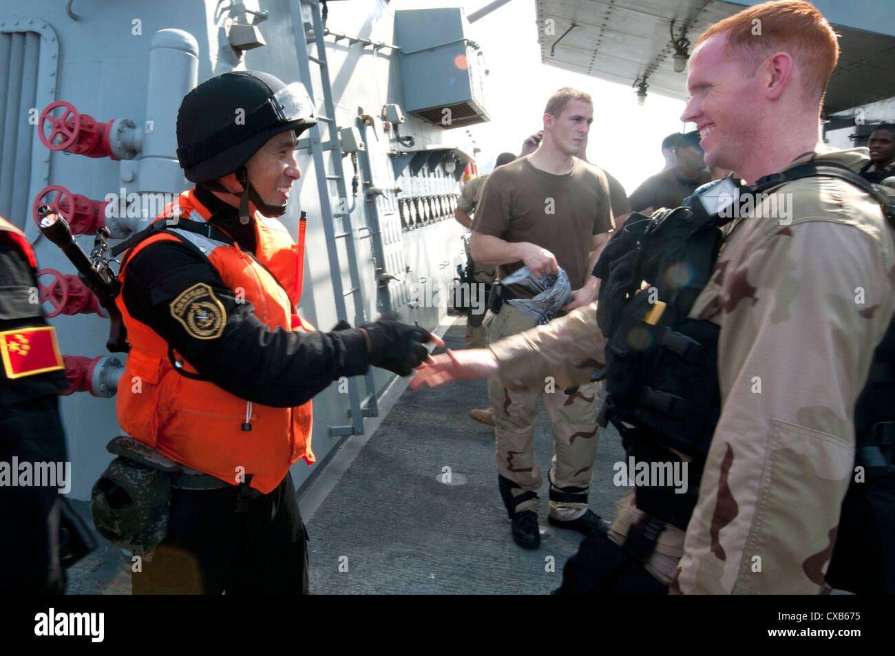 A US special forces team member aboard the guided-missile destroyer USS Winston S. Churchill shakes hands with a special forces member from the Chinese Peoples Liberation Army Navy frigate Yi Yang following a bilateral counter-piracy exercise. The focus of the exercise was American and Chinese naval cooperation in detecting, boarding, and searching suspected pirated vessels. Stock Photo