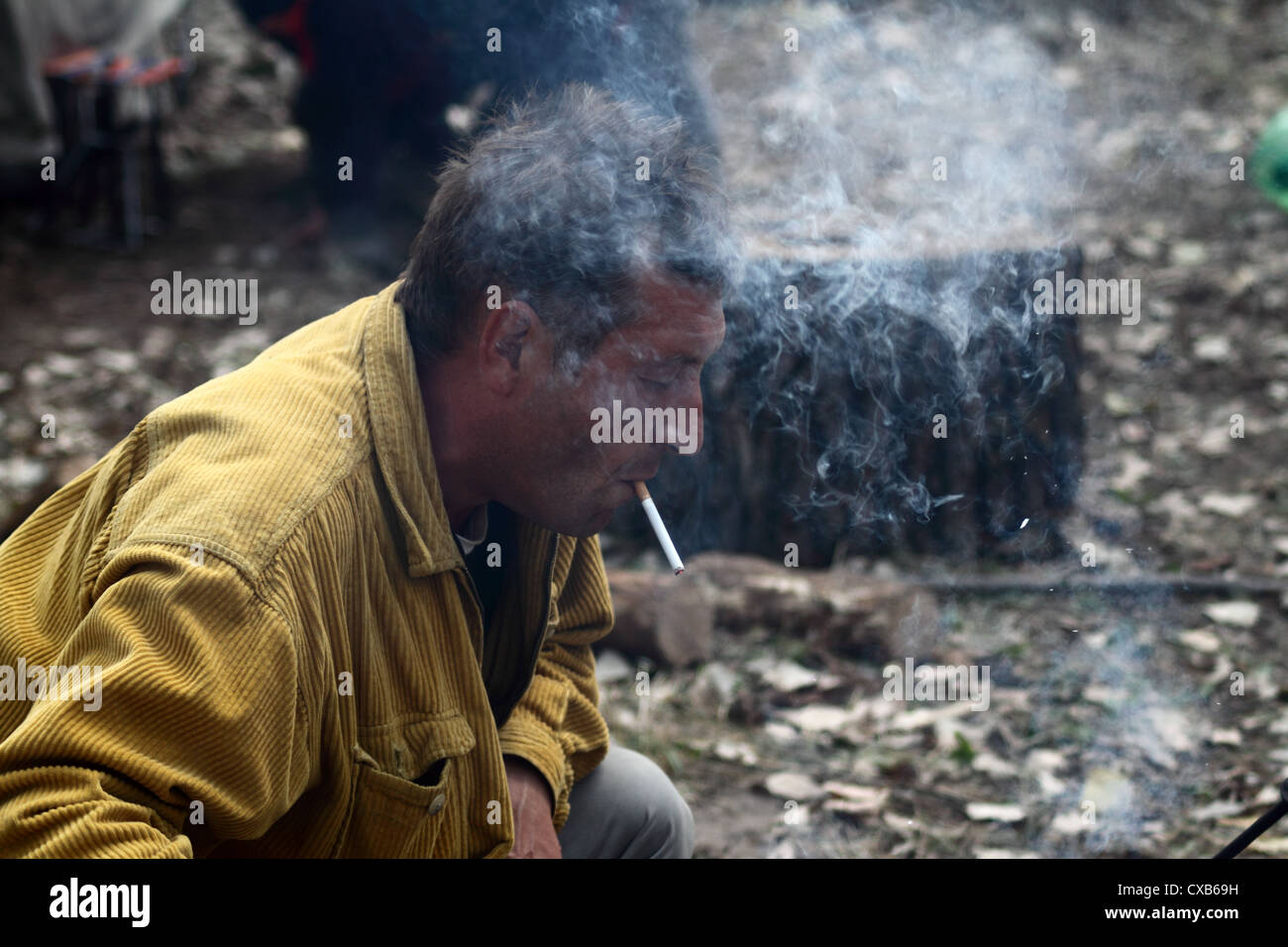 man lights a cigarette with a burning stick Stock Photo