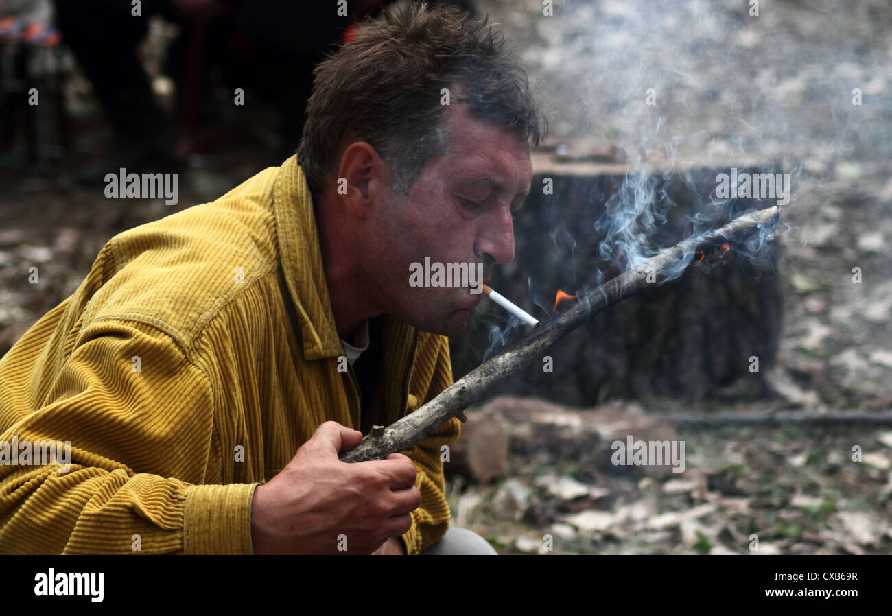man lights a cigarette with a burning stick Stock Photo