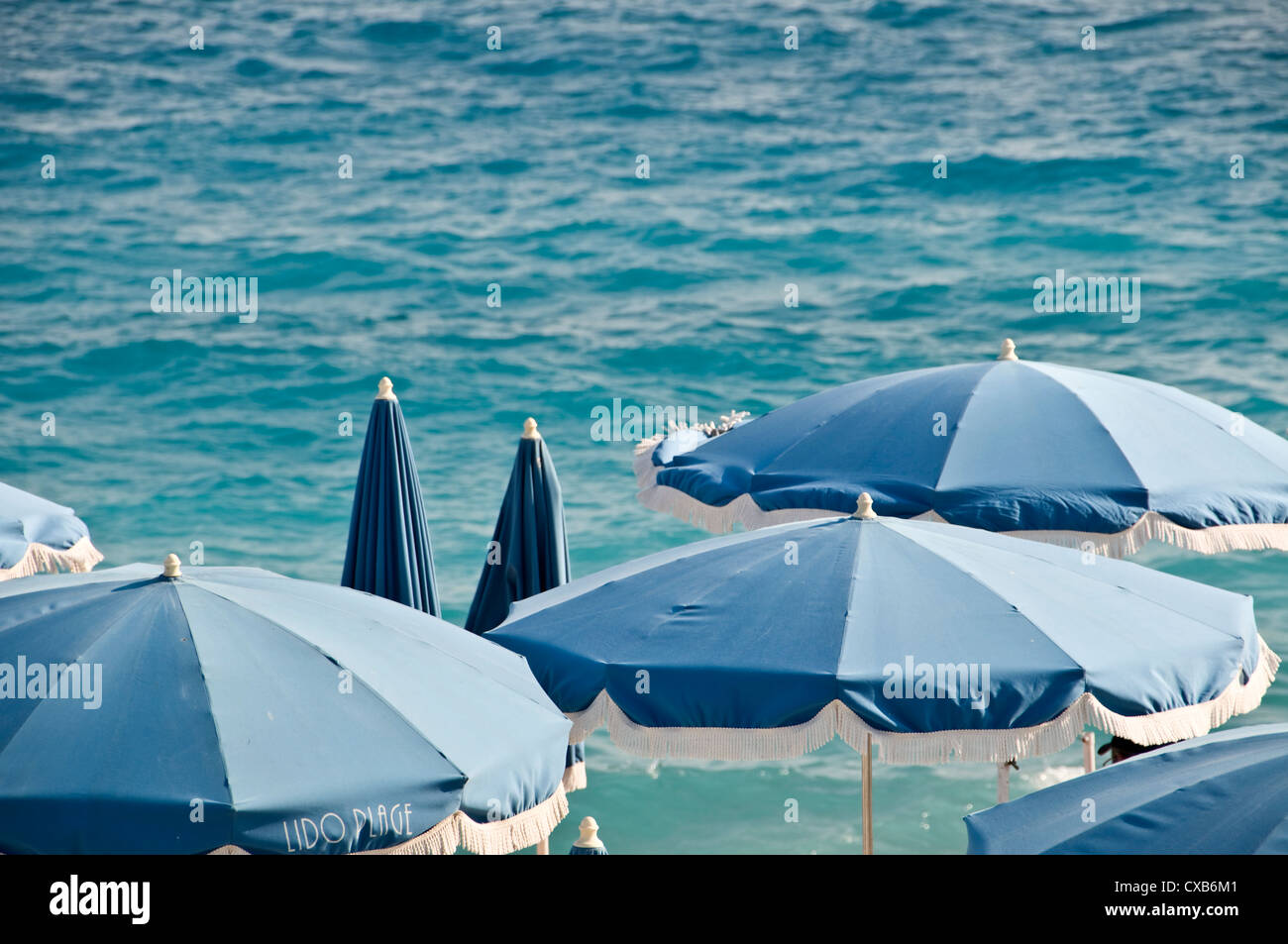 Private beach with blue beach umbrellas, sea in the background view from above - Nice, France Stock Photo