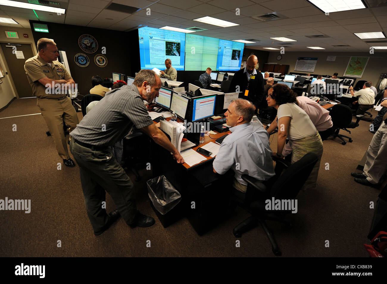Military and civilian personnel from Navy Region Northwest work in the regional operational command center on Naval Base Kitsap, Bangor during emergency preparedness exercise Citadel Rumble 2011. Citadel Rumble is an annual exercise intended to improve an installation's ability to respond to a natural disaster and maintain a high level of readiness. The identification of the man in the center of the photo has been digitally altered for security reasons. Stock Photo