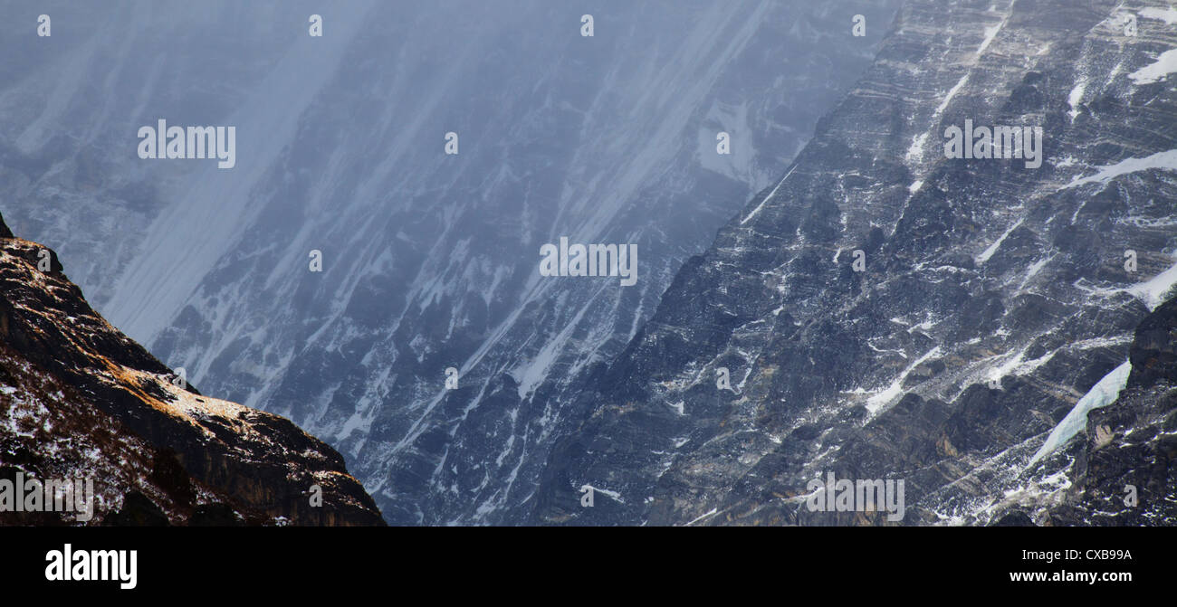 Mist and fog sweeping over the side of a mountain covered in snow ...