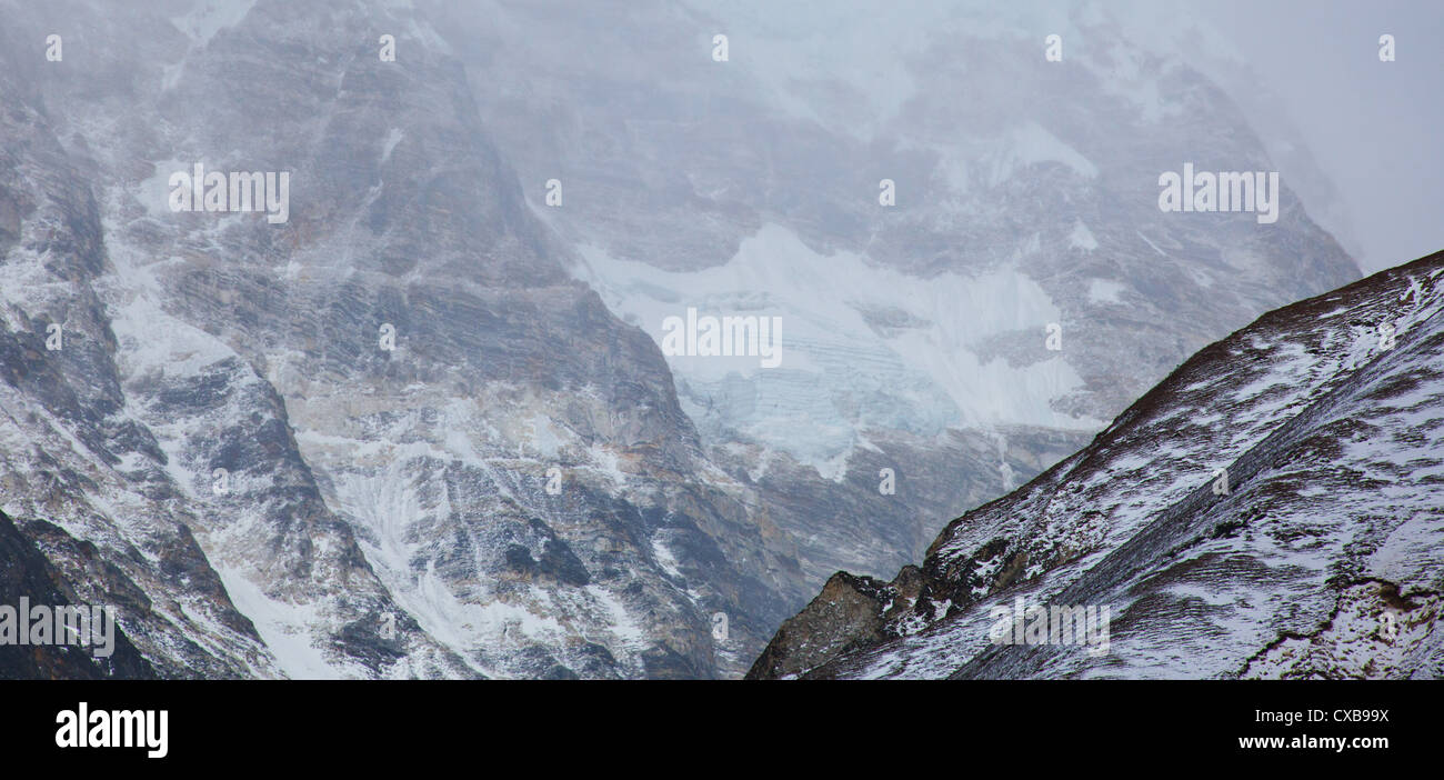 Mist and fog sweeping over the side of a mountain covered in snow, Langtang Valley, Nepal Stock Photo