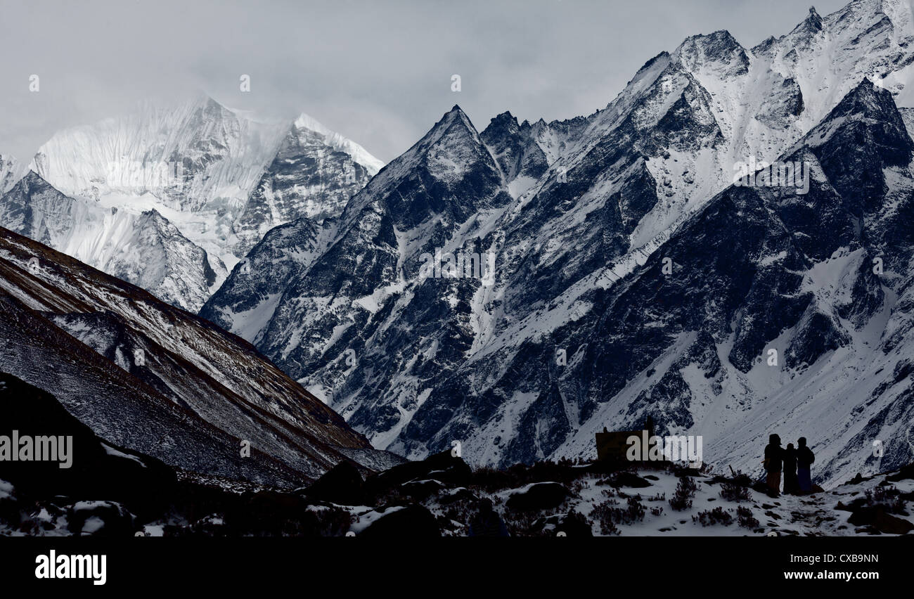 Trekkers standing beneath snowcapped mountains along the Langtang Valley, Nepal Stock Photo