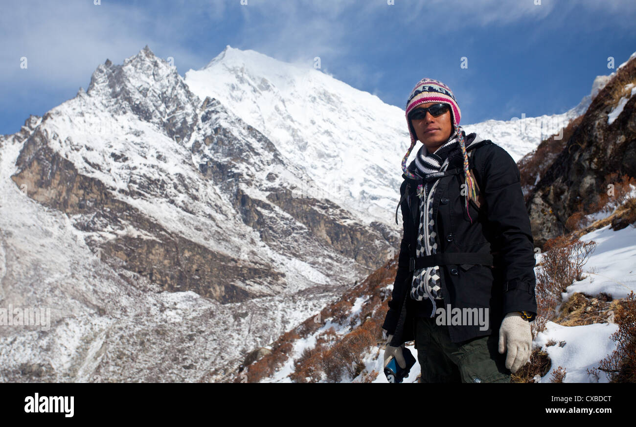 Young Nepali man standing in front of a snowcapped mountain, Langtang Valley, Nepal Stock Photo