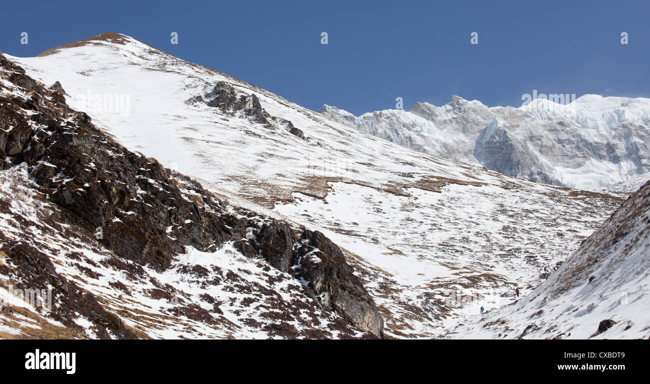 People trekking up the side of a mountain covered in snow, Langtang ...