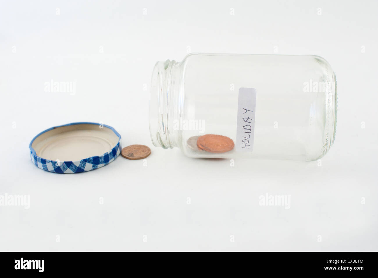 A near empty glass jar of money with 'holiday' label. Stock Photo