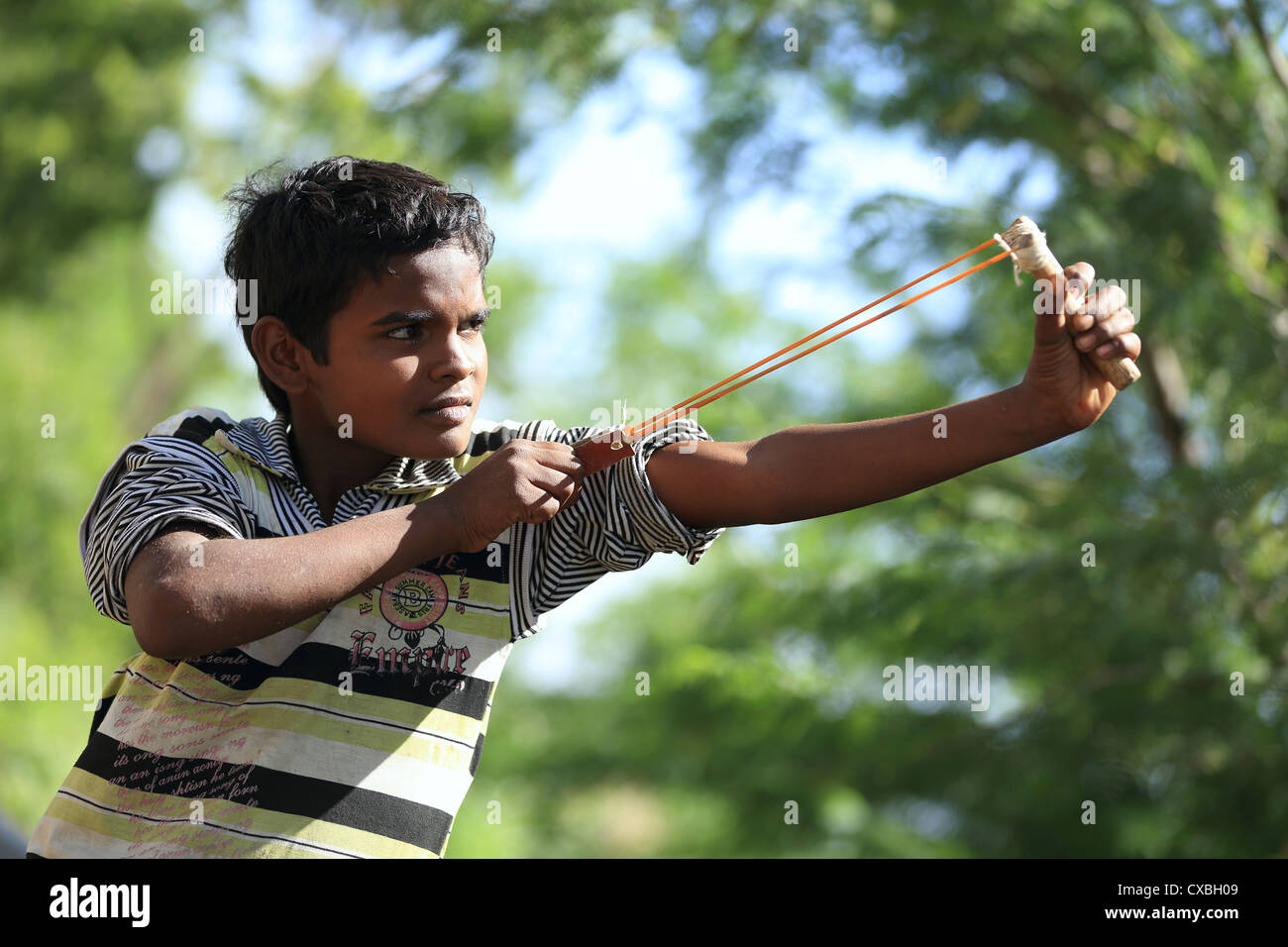 Indian boy with a slingshot trying to kill birds Andhra Pradesh South India Stock Photo