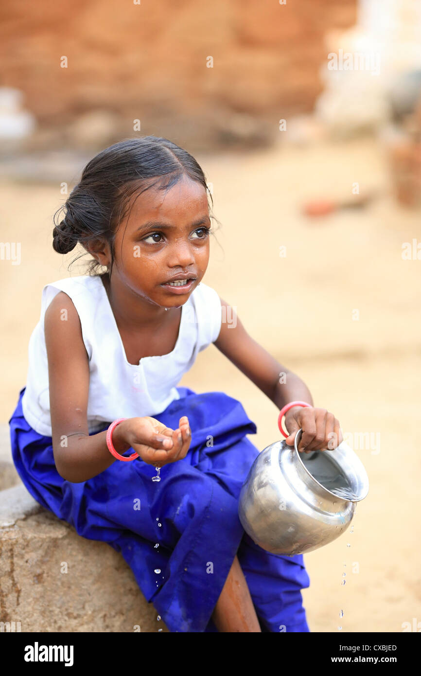 Indian school girl with water pot rinsing her mouth and washing her
