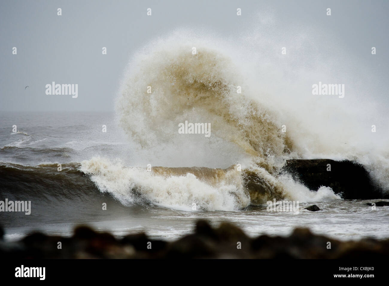 Waves crash over rocks in an area known as South Gare on Teesside in England as heavy seas lash the coastline. Stock Photo