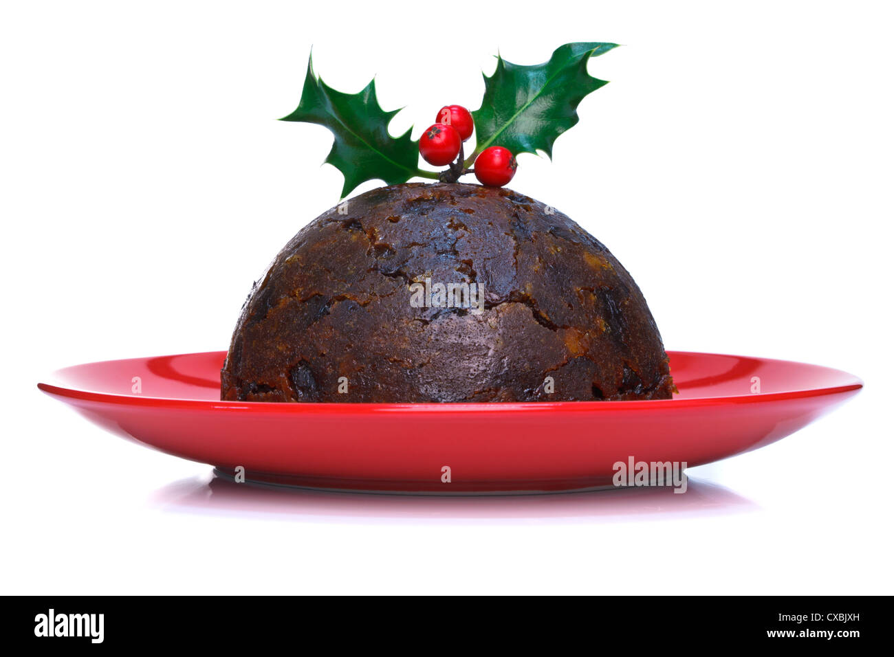Photo of a steamed Christmas pudding with holly on top isolated on a white background. Stock Photo
