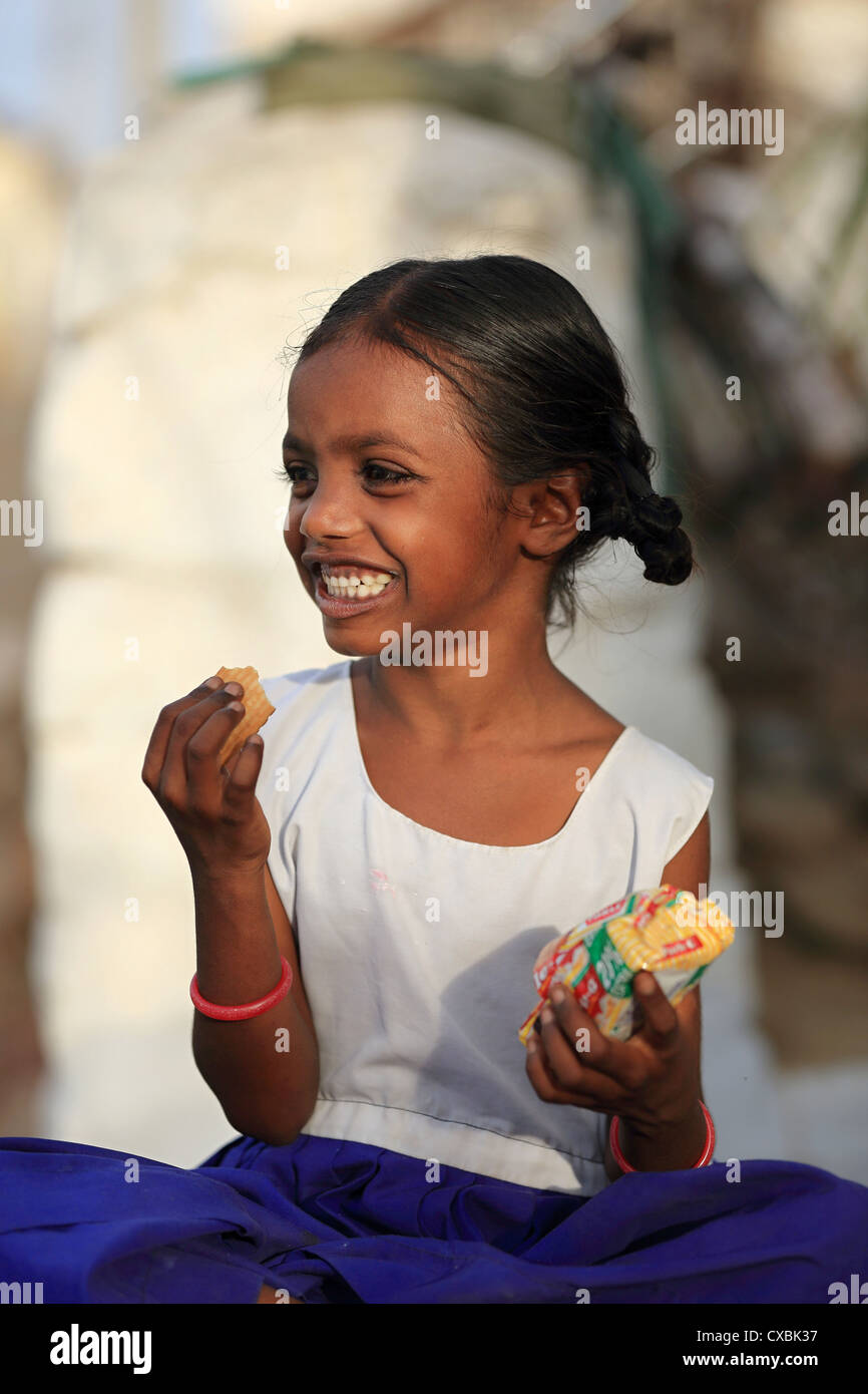 Indian school girl Dhanama eating Parle biscuits Andhra Pradesh South India Stock Photo