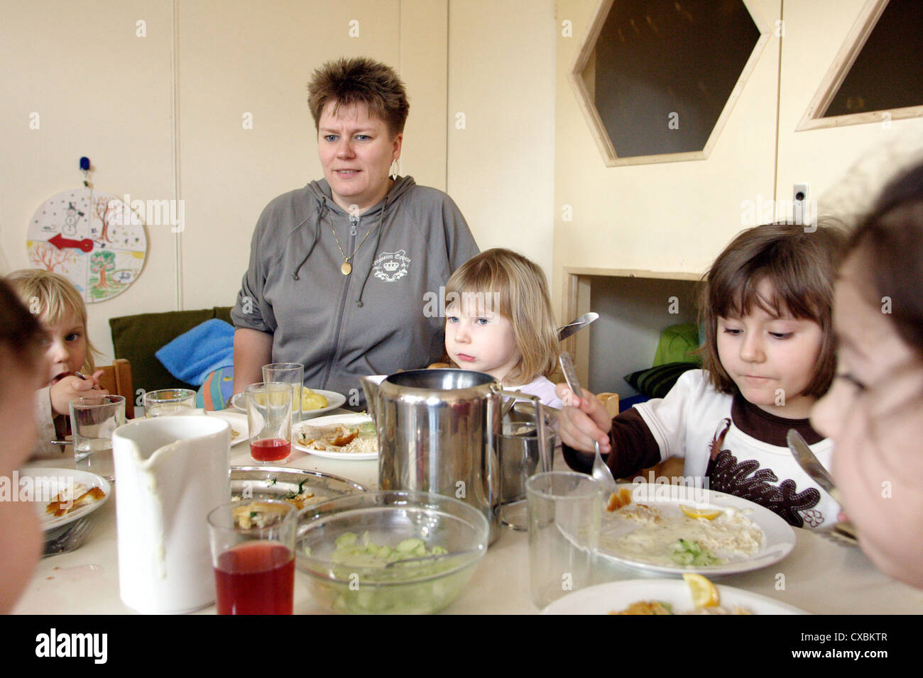 Berlin, children sit with a teacher at the table and eat lunch Stock Photo