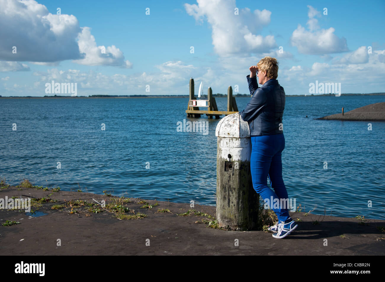 blue dressed woman thinking and staring at sea to the boats Stock Photo