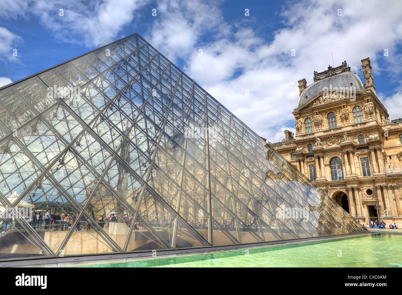 Famous glass Pyramid and Louvre Museum (former Royal Palace) on background in Paris, France. Stock Photo