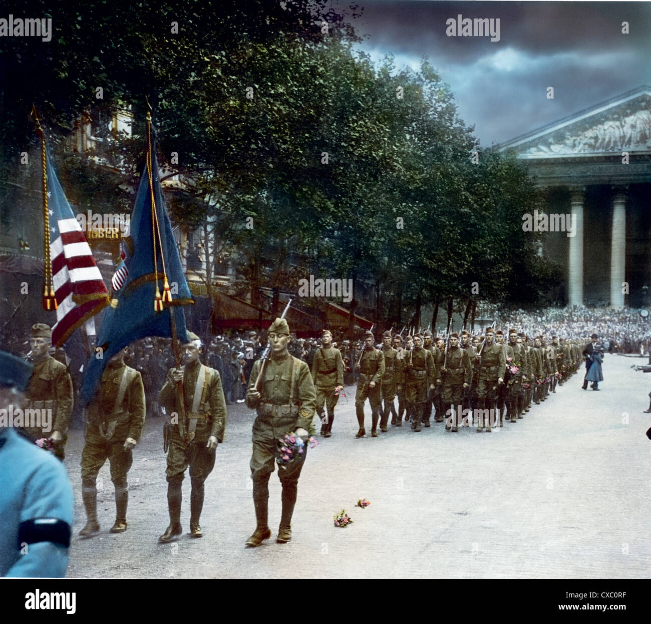 Colorized photo of American soldiers marching on the Place de la Madeleine in an Armistice Day parade, Paris, France, November 11th, 1918. Some of the soldiers hold flowers. (Photo by Burton Holmes) Stock Photo