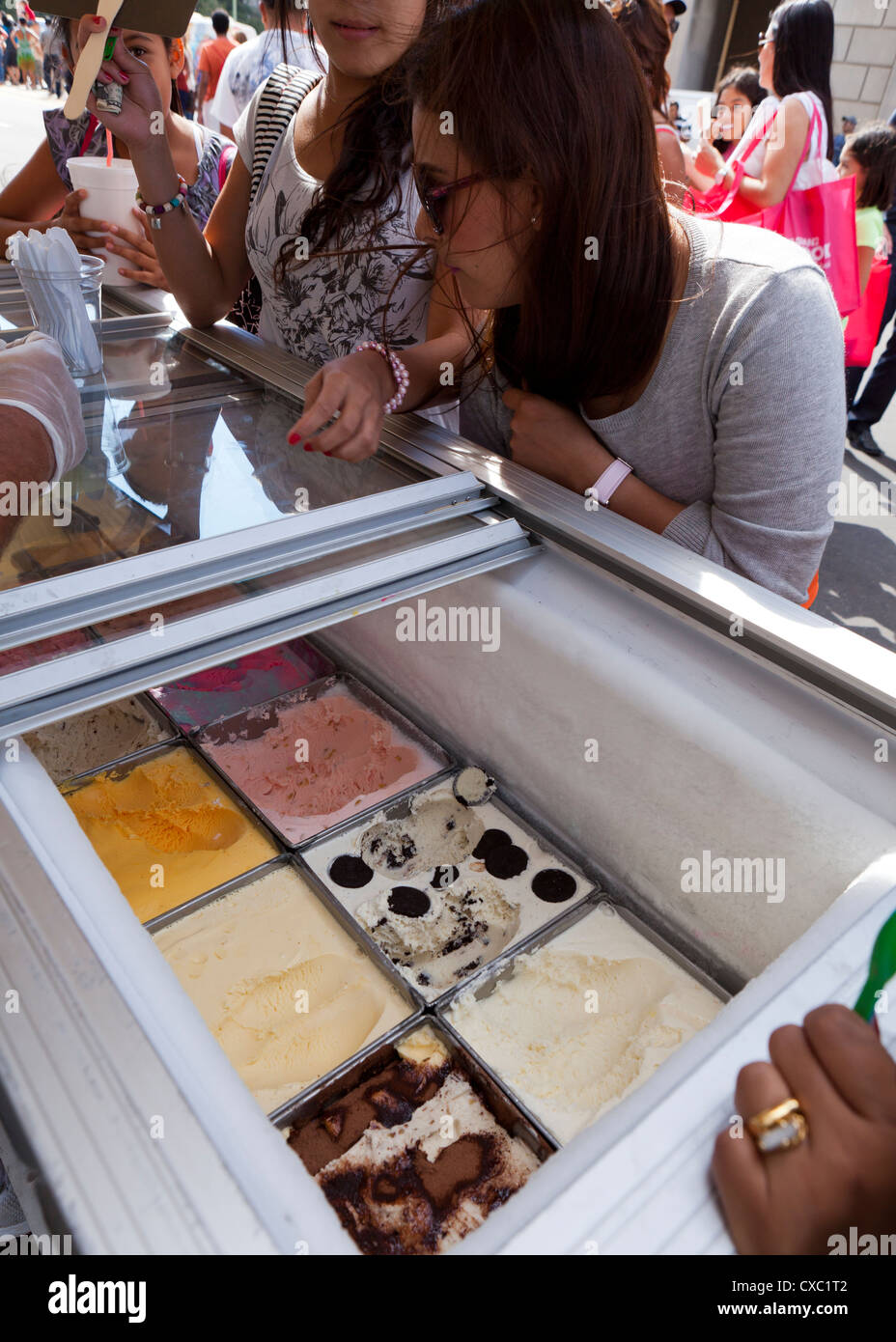 Young women contemplating ice cream flavors at an outdoor festival Stock Photo