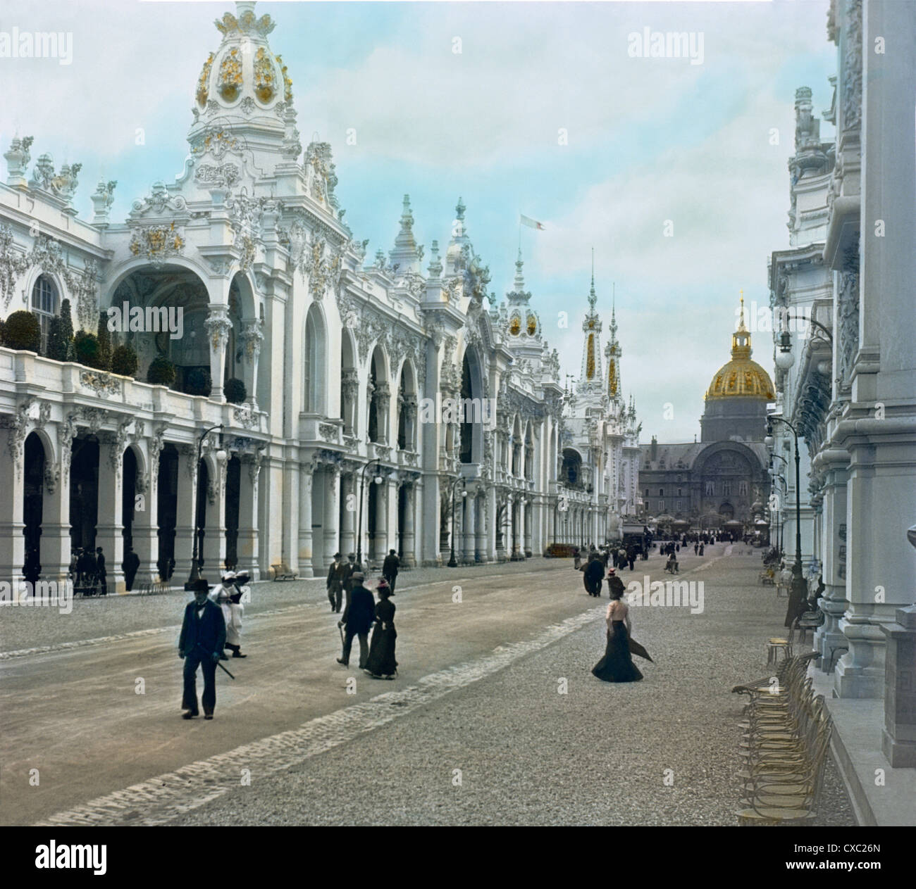 Colorized view of exhibition visitors walking on the Esplanade des Invalides during the 1900 Paris Exposition, also known as Exposition Universelle of 1900, Paris, France, 1900. Various palaces / pavilions are along both sides of the esplanade and the dome of Les Invalides is seen in the distance. (Photo by Burton Holmes) Stock Photo