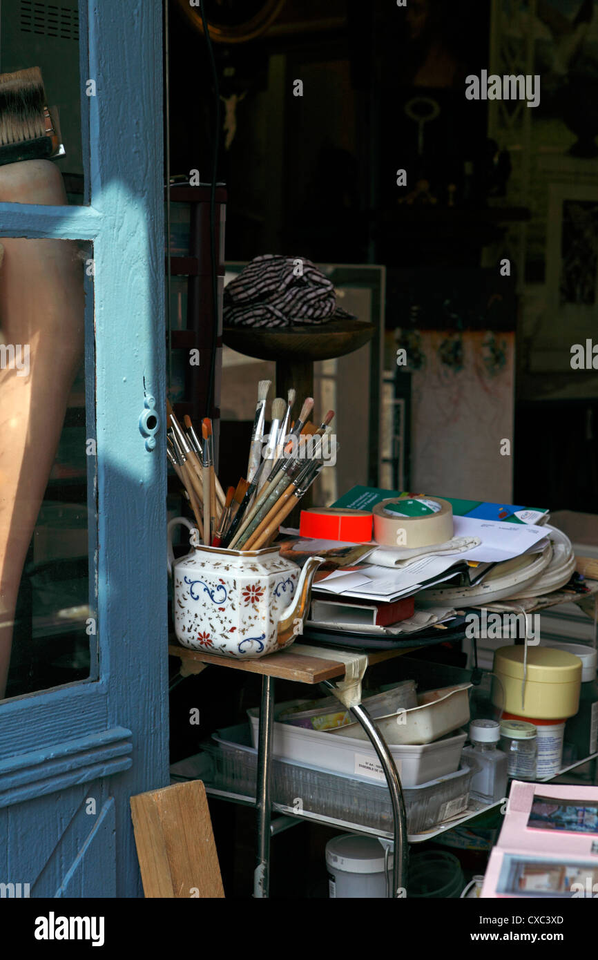 generic image of artists brushes in an old teapot by an open door, the entrance to an untidy studio Stock Photo