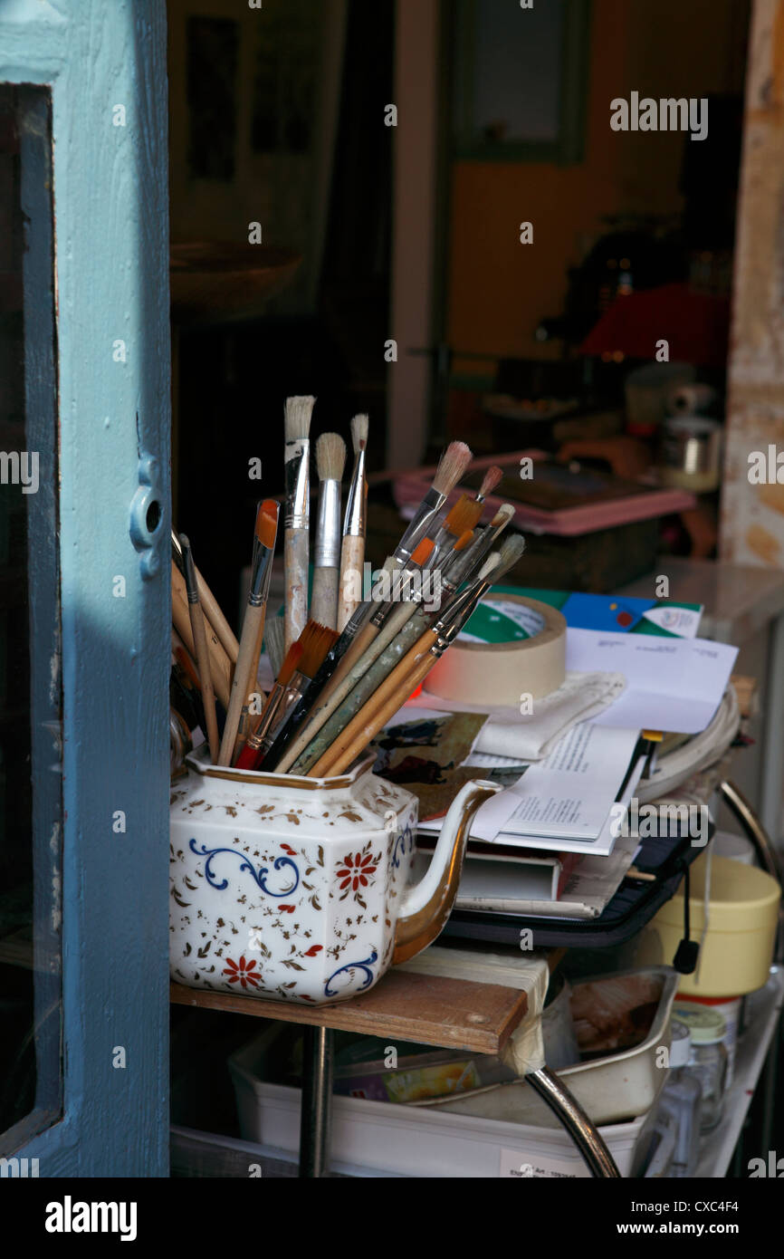 generic image of artists brushes in an old teapot by a window Stock Photo
