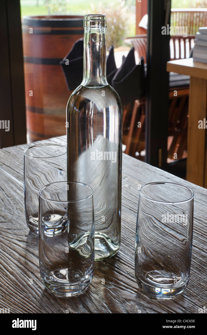 A bottle of water and three glasses in a on a wooden table Stock Photo ...