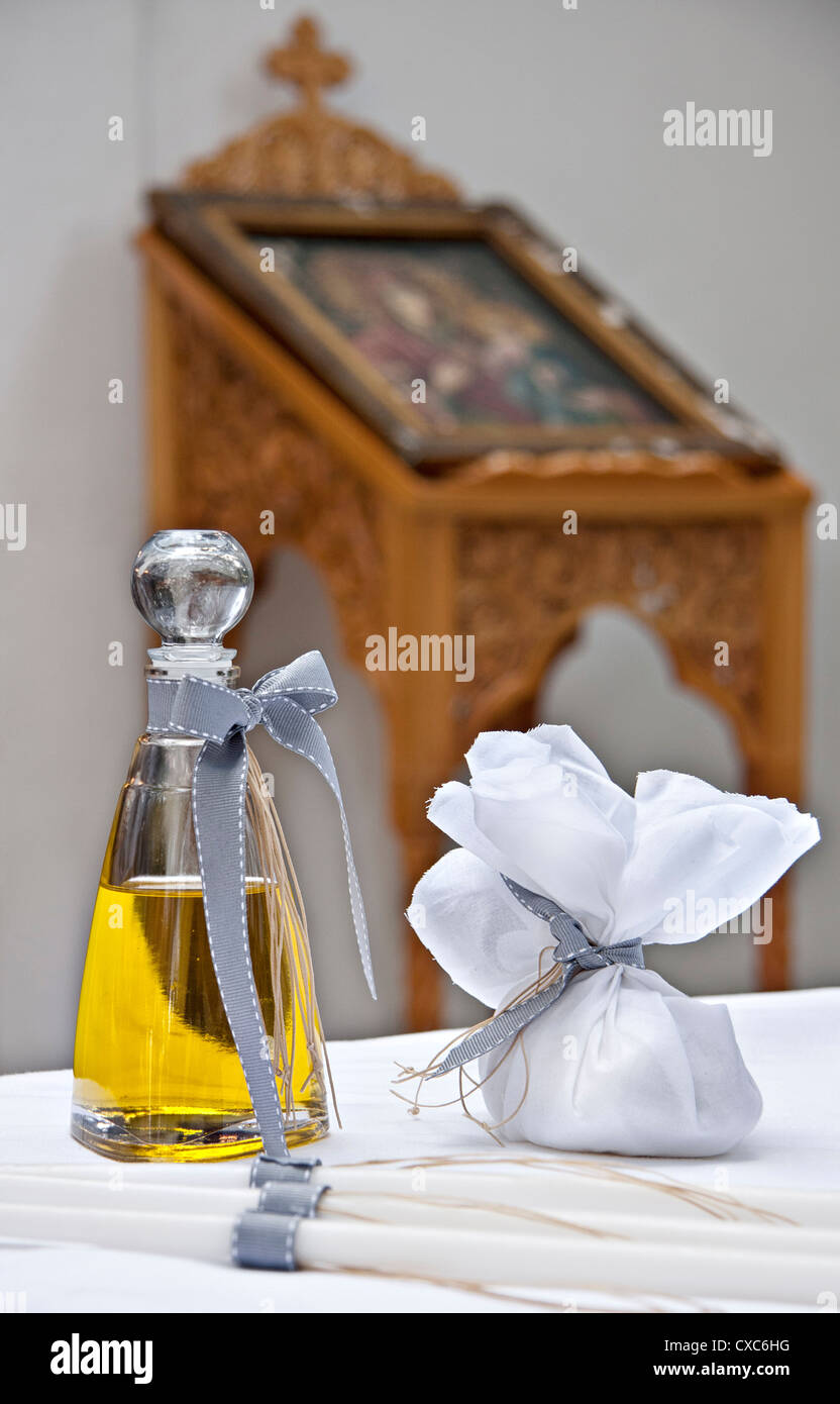 Attributes for Greek orthodox baptism- candles, bottle of olive oil soap. At the background icon of Holy Mary /Panagia Stock Photo