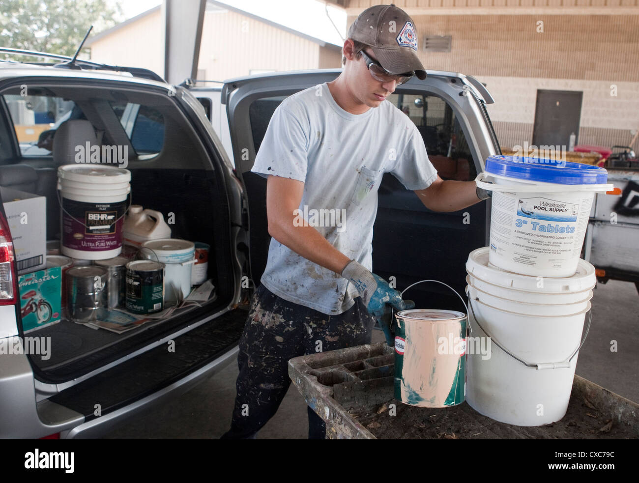 Male employee at the City of Austin household hazardous waste facility unloads paint from resident to properly dispose of Stock Photo