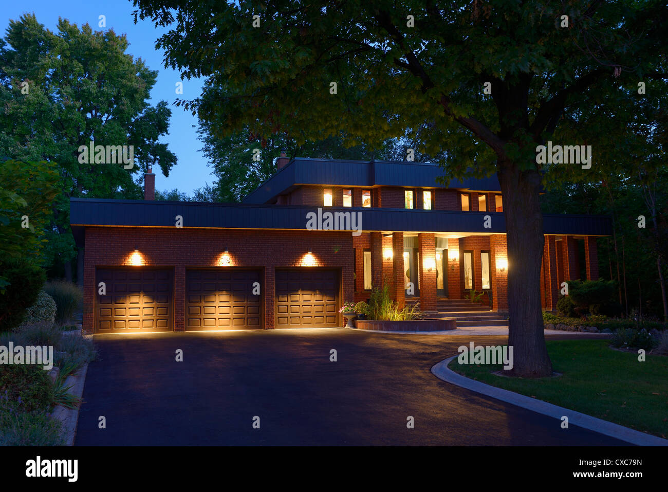 https://c8.alamy.com/comp/CXC79N/red-brick-house-with-circular-driveway-and-three-car-garage-at-twilight-CXC79N.jpg
