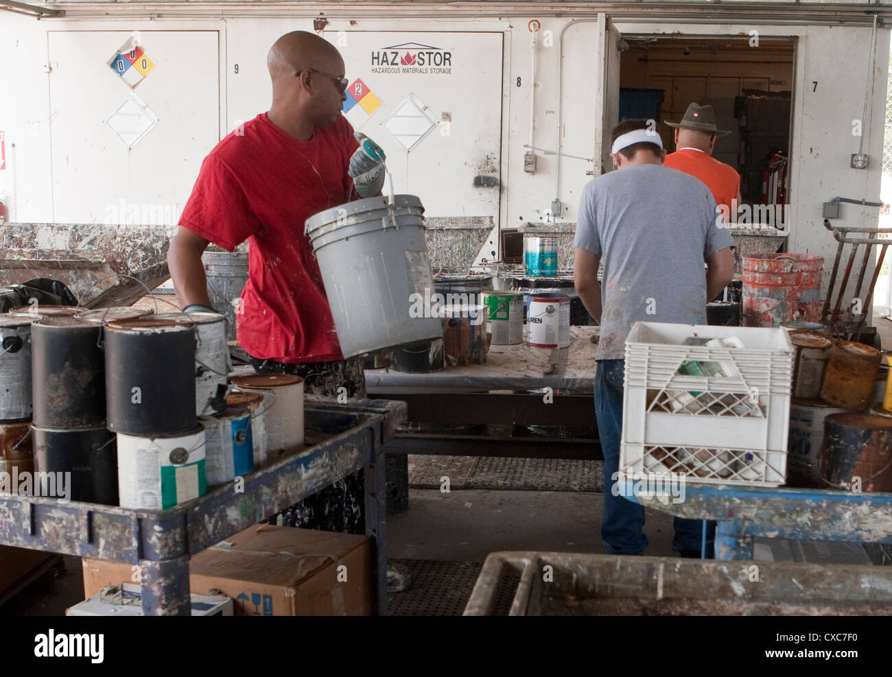 Male employee at the City of Austin household hazardous waste facility unloads paint from resident to properly dispose of Stock Photo