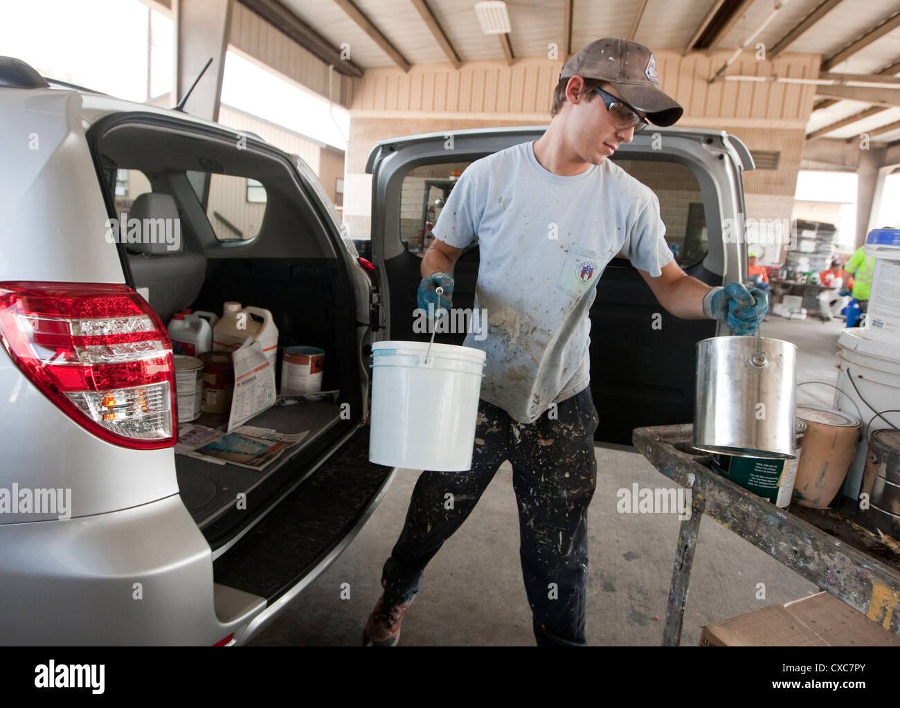 Male employee at the City of Austin household hazardous waste facility unloads paint from resident to properly dispose of Stock Photo