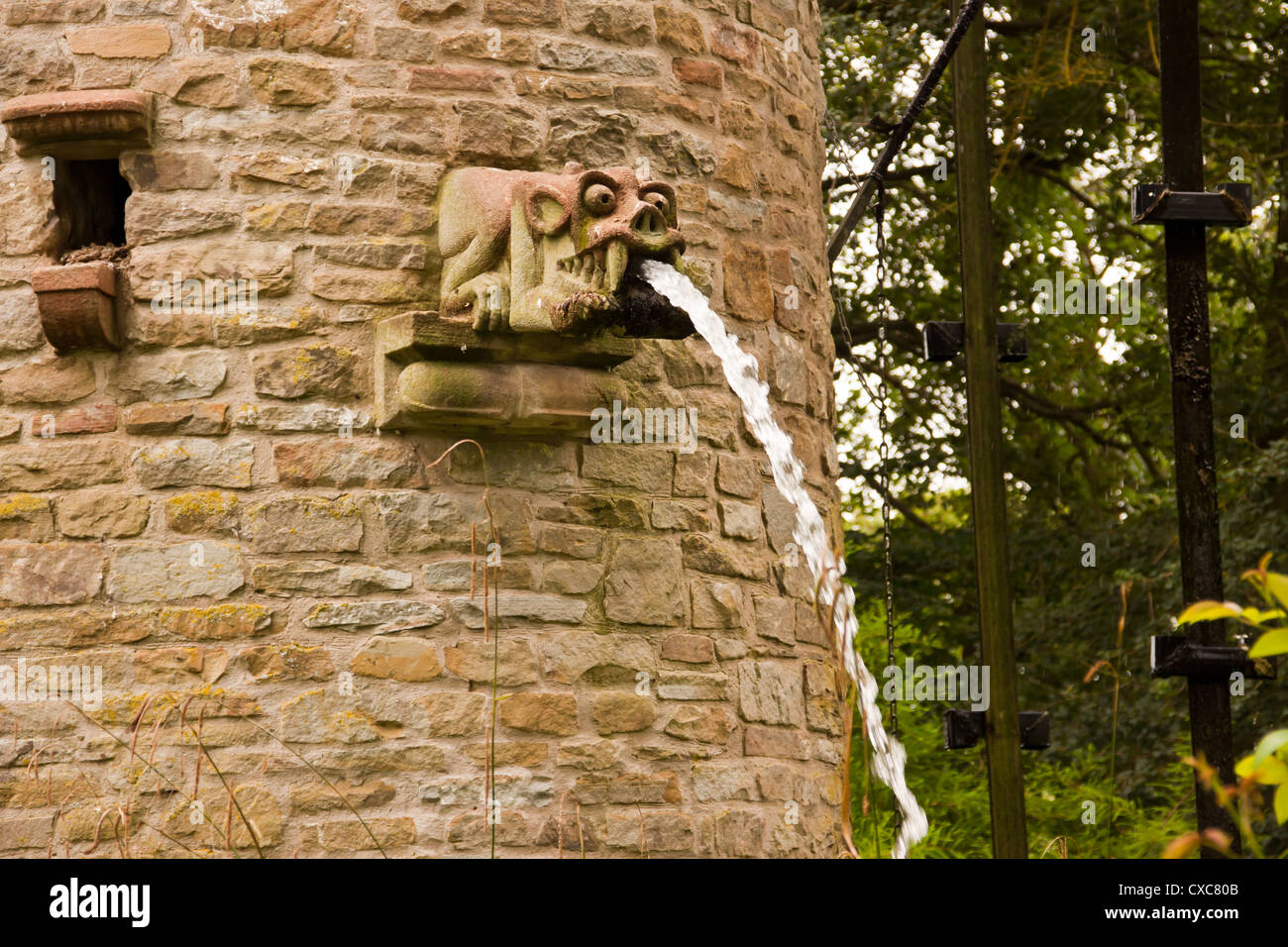 Stone tower with water feature and dove coot and water spouting gargoyles, Westonbury Mill water gardens, Pembridge, Herefordshi Stock Photo