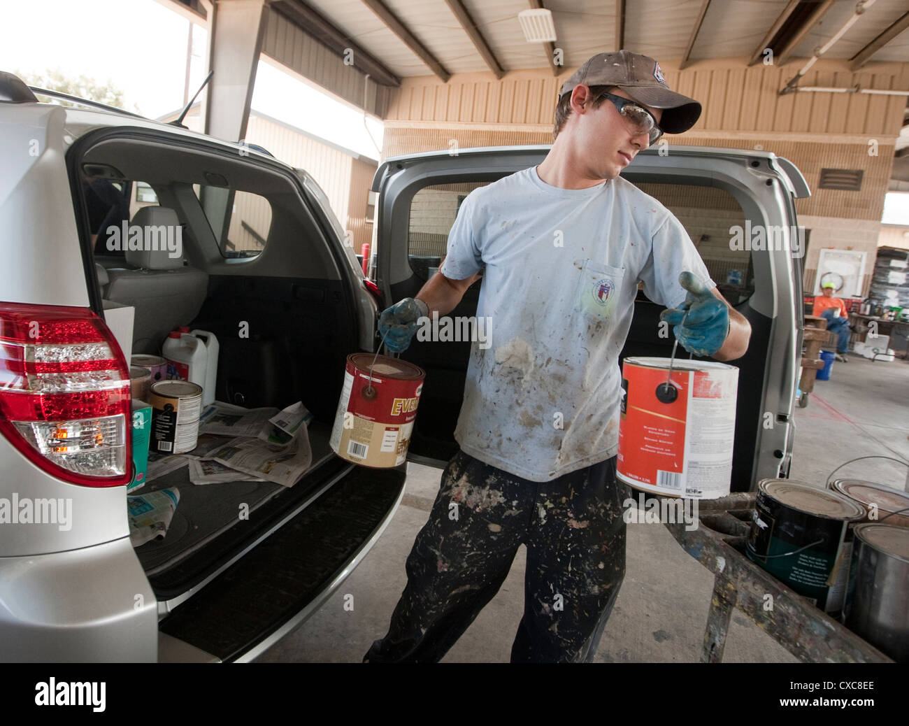 Male employee at the City of Austin household hazardous waste facility unloads paint from resident to properly dispose of Stock Photo