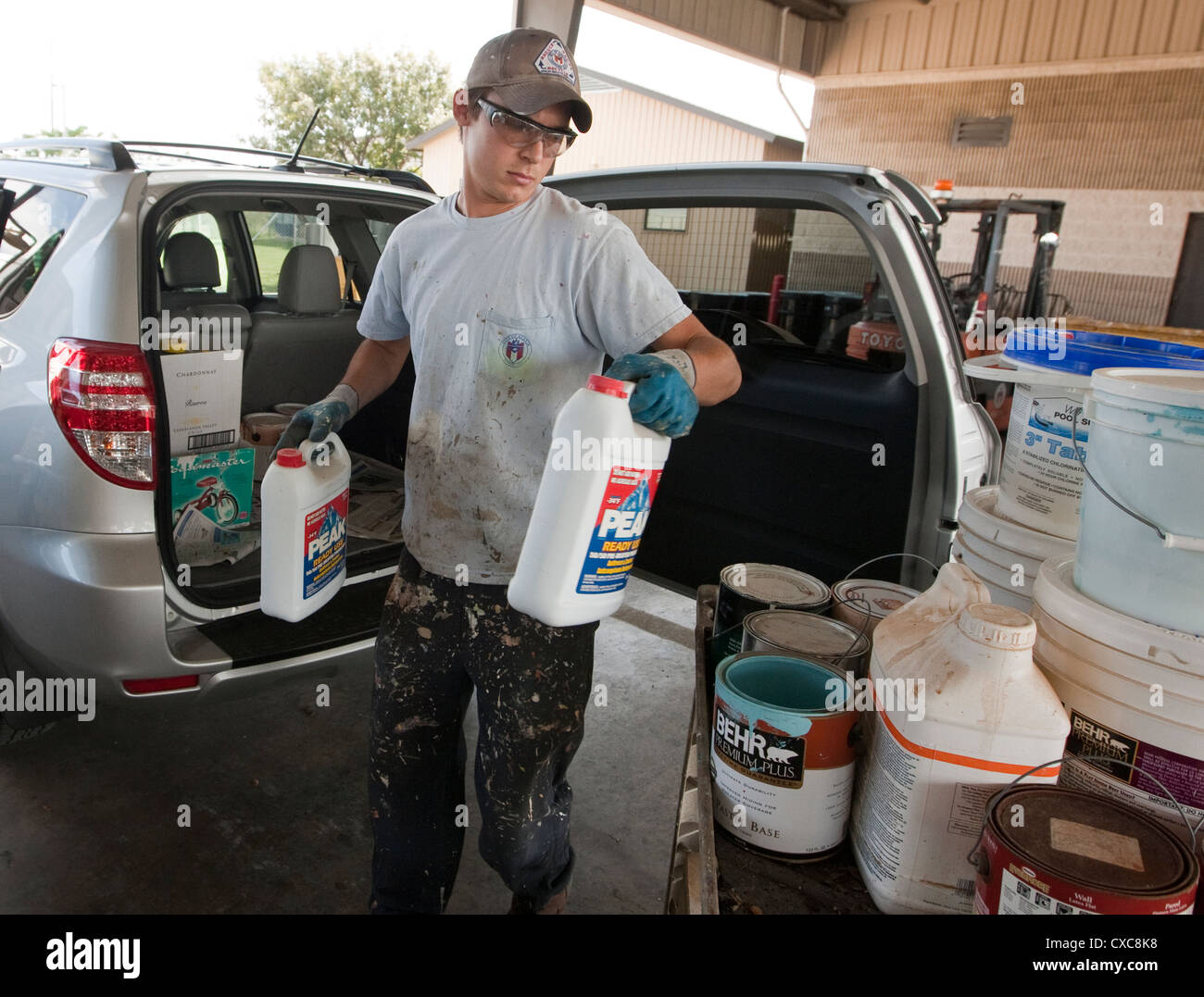 Male employee at the City of Austin household hazardous waste facility unloads paint from resident to properly dispose of Stock Photo