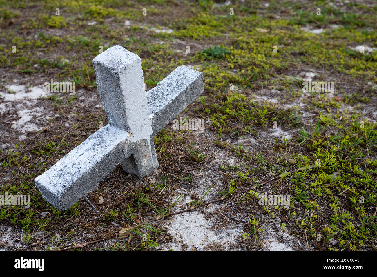 Buried Cross. A cross shaped grave marker partially buried in the shifting sand of the Hopetown Graveyard. Stock Photo