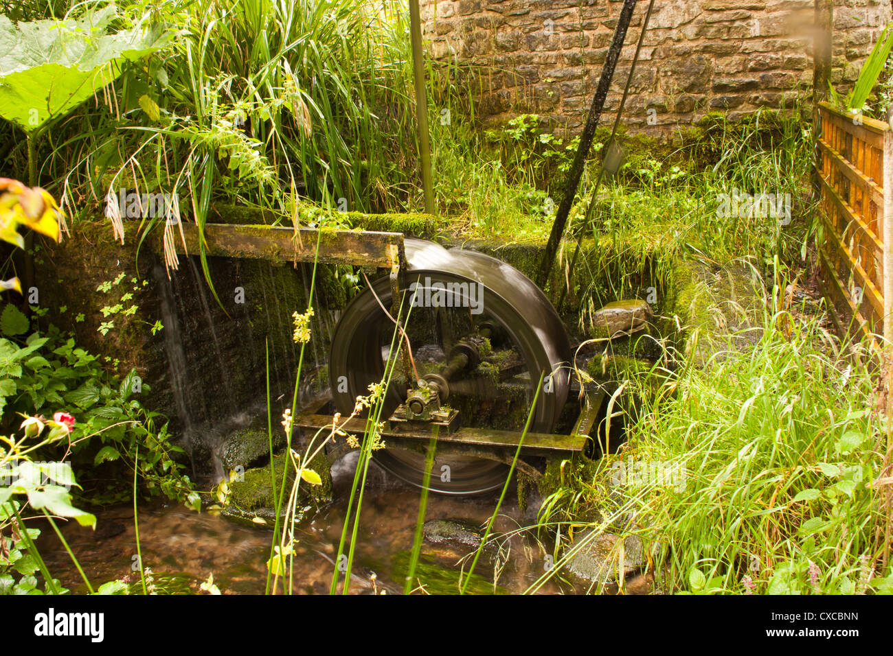 Water Mill powering water feature at Westonbury Mill Water Gardens Pembridge Herefordshire UK. Stock Photo