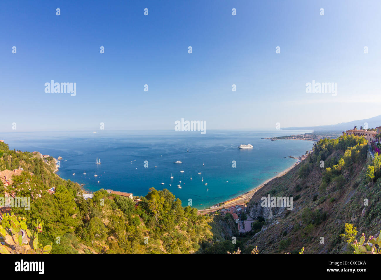 Sicilian seascape from Taormina: mount Etna beyond the blue sea and trees frame on foreground Stock Photo