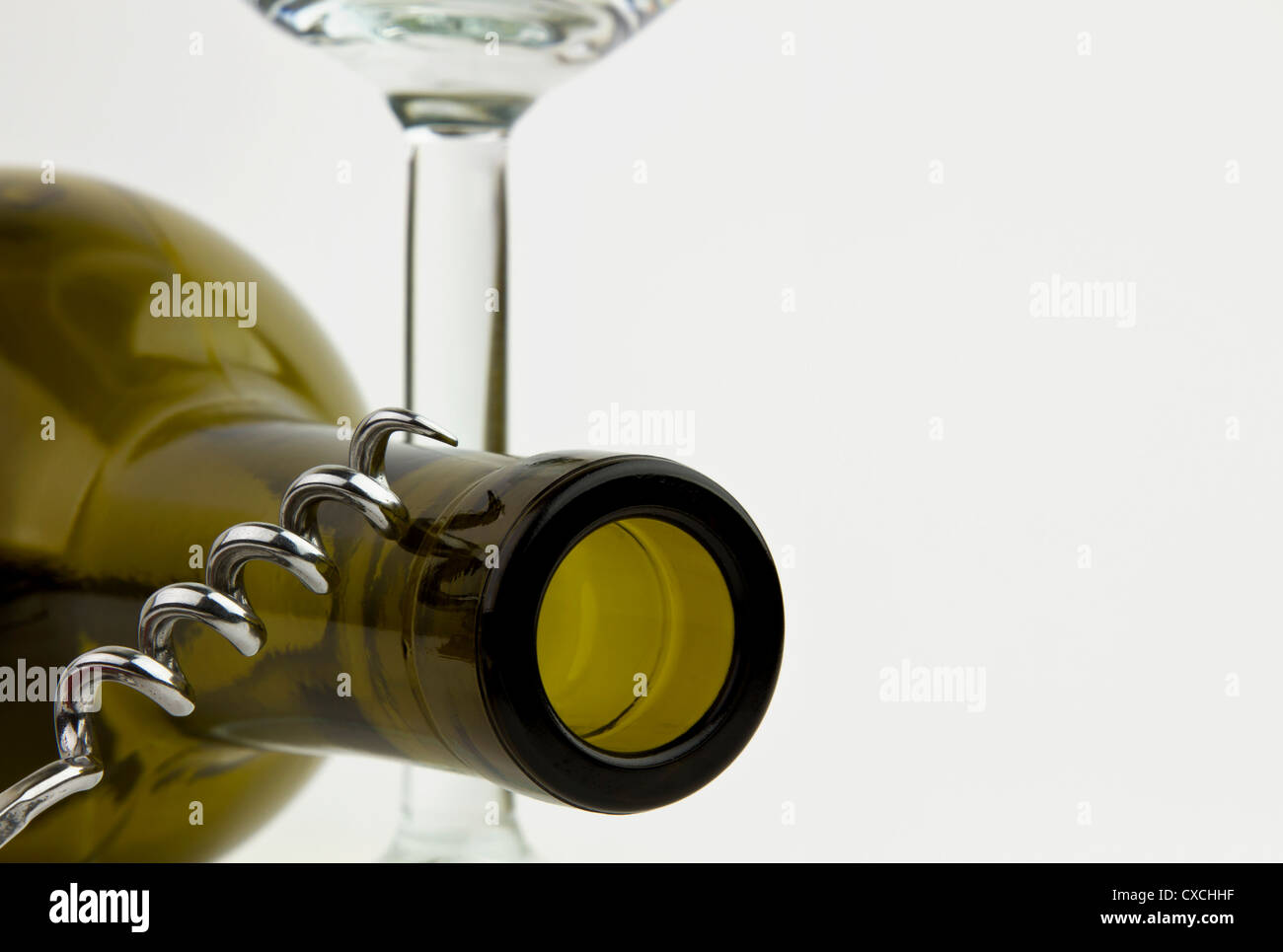 Empty green glass wine bottle with stem wineglass and corkscrew. Stock Photo