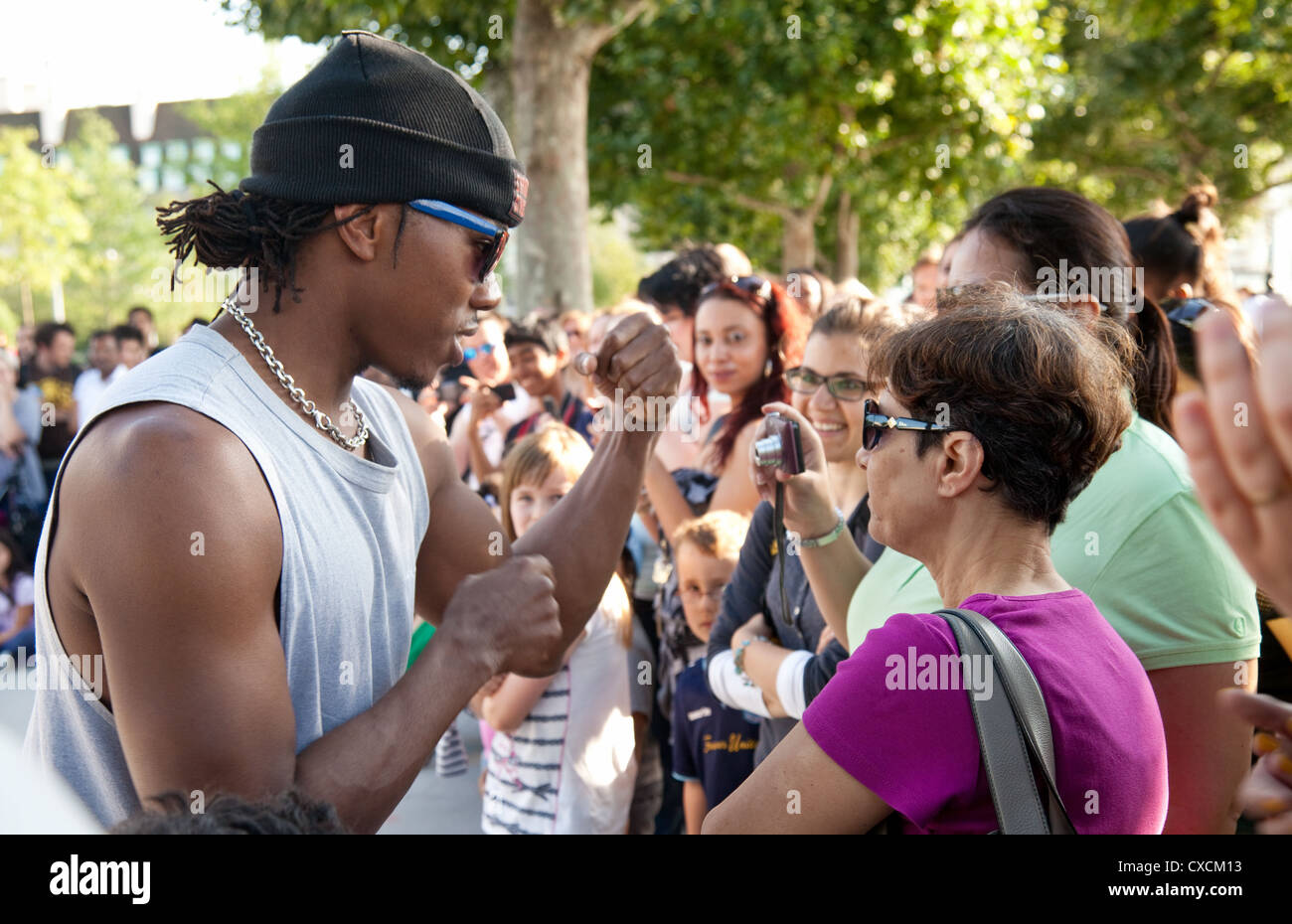 A black male  street performer facing a woman in the crowd, South Bank, London, UK Stock Photo