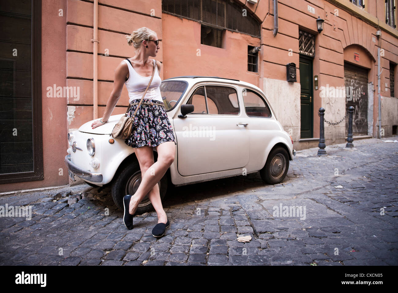 Woman standing next to Fiat 500 on the streets of Rome, Roma, Italy, Italia, Europe Stock Photo