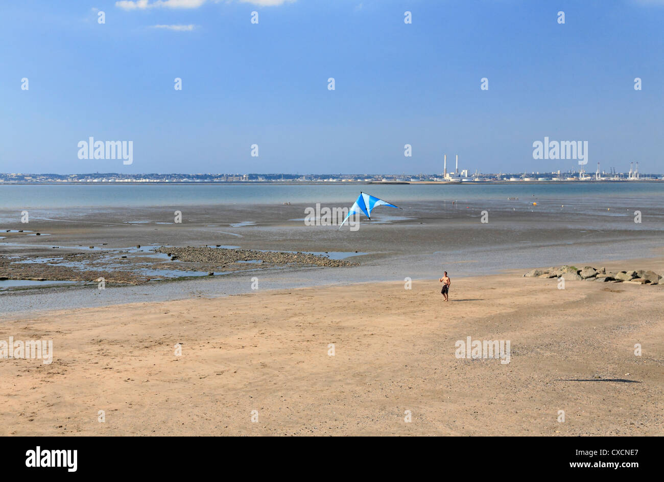 Man flying kite Villerville beach Normandy The Cote Fleurie River Seine estuary overlooking industrial port of le Havre Stock Photo